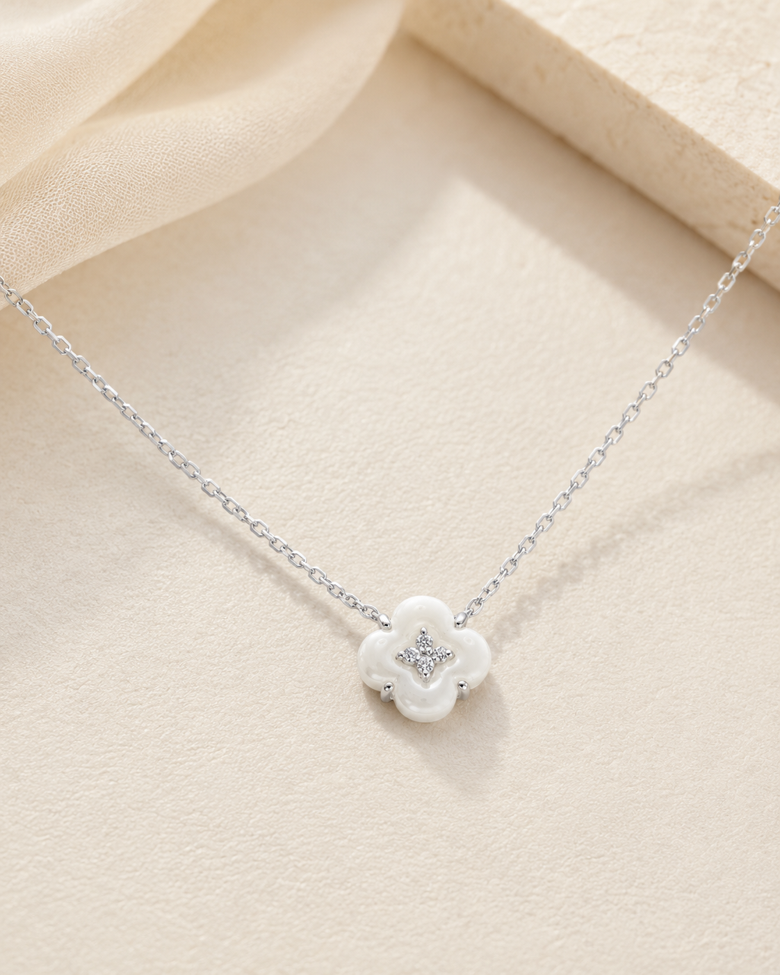 CARV. silver mother-of-pearl flower necklace with white floral pendant displayed on beige surface