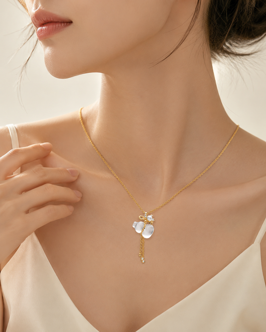 CARV. gold pendant necklace with white crystal charm and tassel detail worn at collarbone close-up
