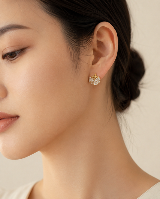 CARV. gold floral leaf stud earrings with pavé crystal cluster worn on ear close-up