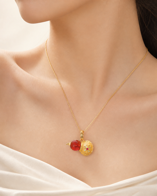 CARV. gold gourd pendant necklace with red bead and engraved round charm worn on neckline close-up