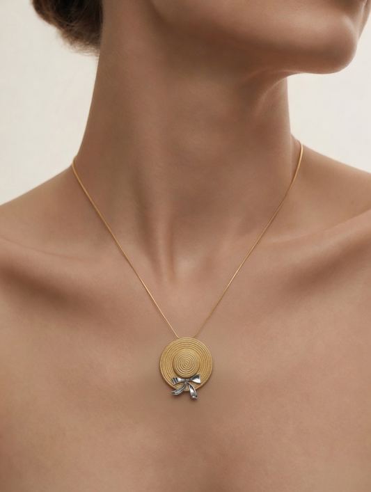 CARV. gold straw hat pendant necklace worn at collarbone with spiral pendant and silver bow