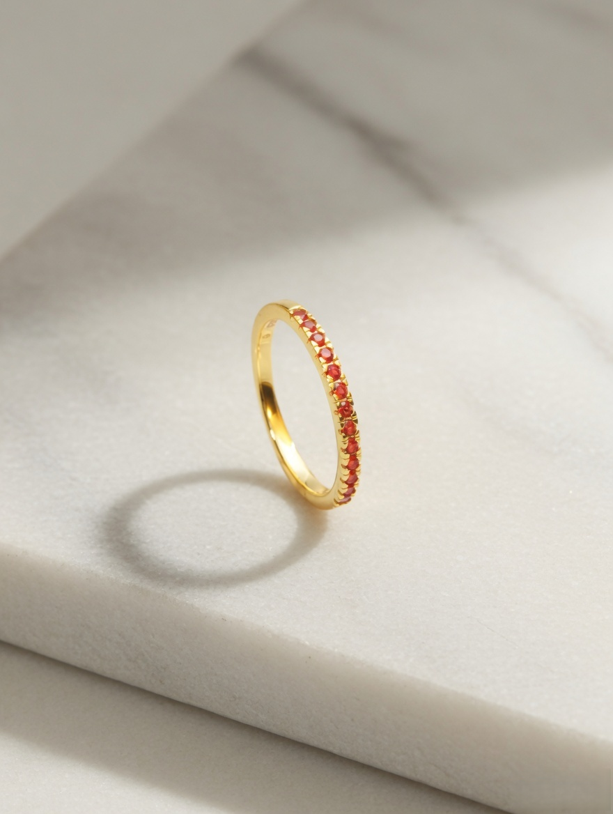 CARV. gold red stone band ring displayed on stone surface with slim band and red stone setting