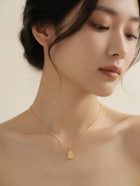 CARV. gold filigree gourd pendant necklace worn at collarbone close-up