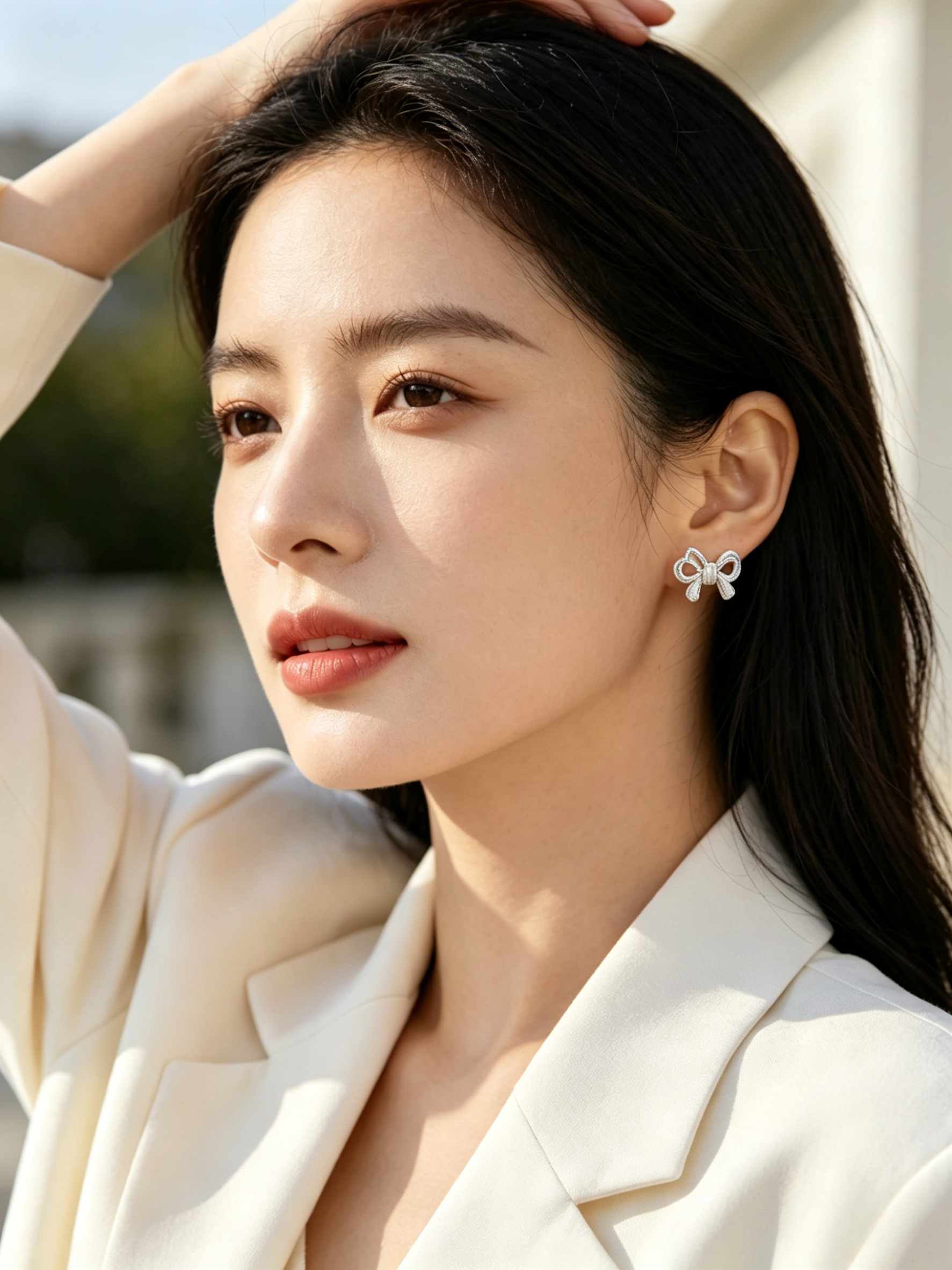 CARV. silver bow stud earrings shown on ear in portrait view with polished ribbon design