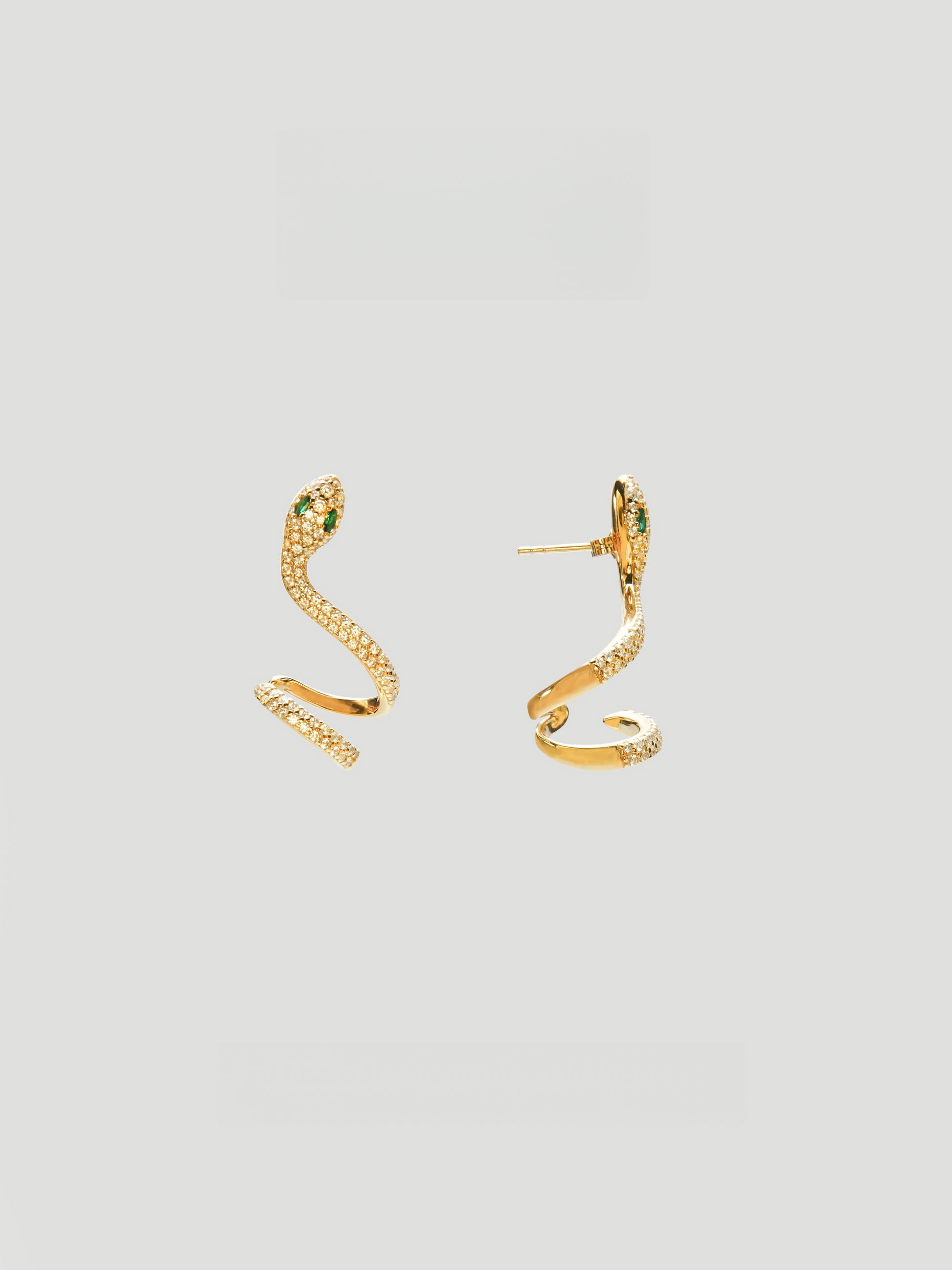 CARV. gold snake curve earrings with pavé texture, sculptural serpent shape and green eye detail