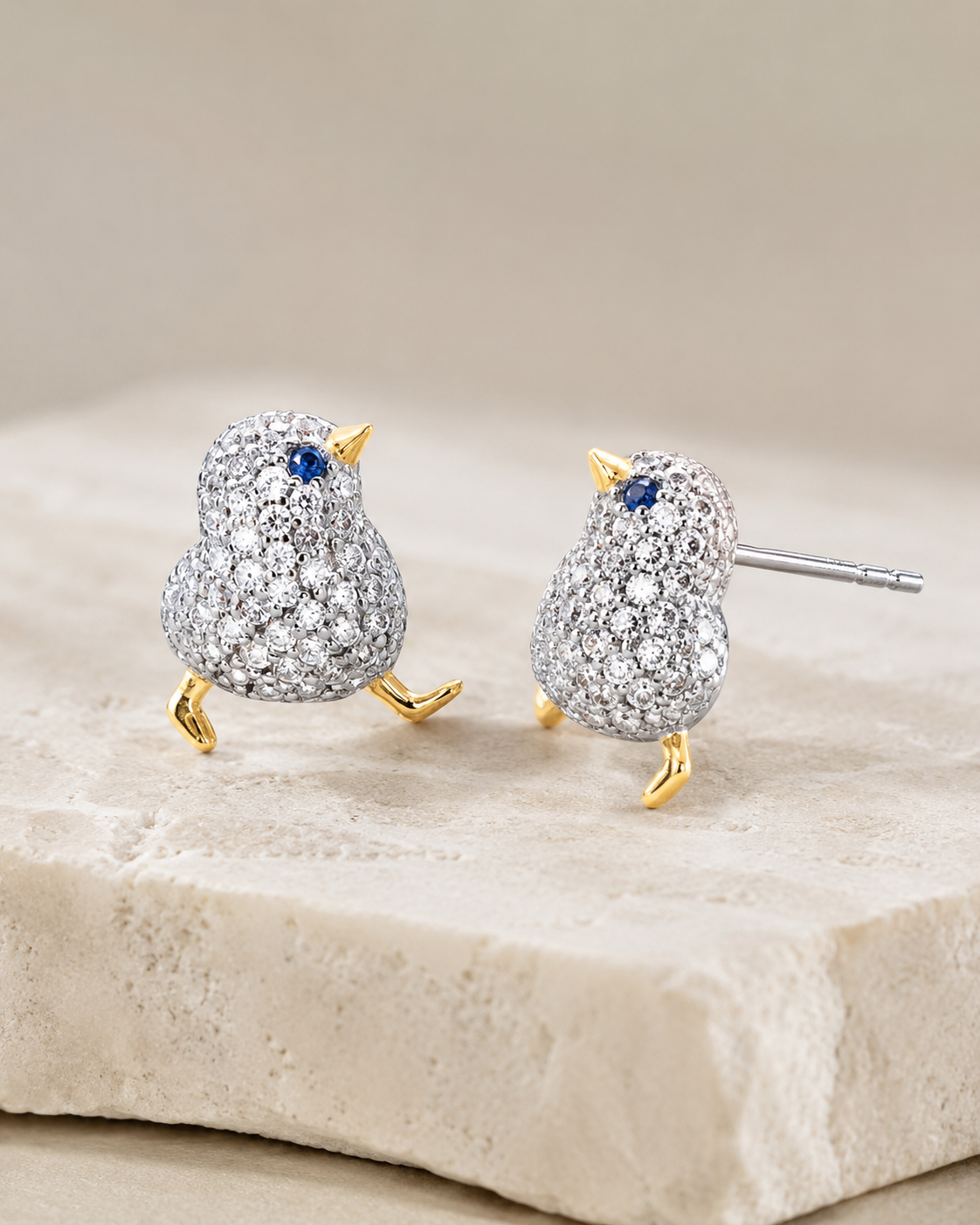 CARV. two-tone bird stud earrings with blue stone eye product display on stone surface