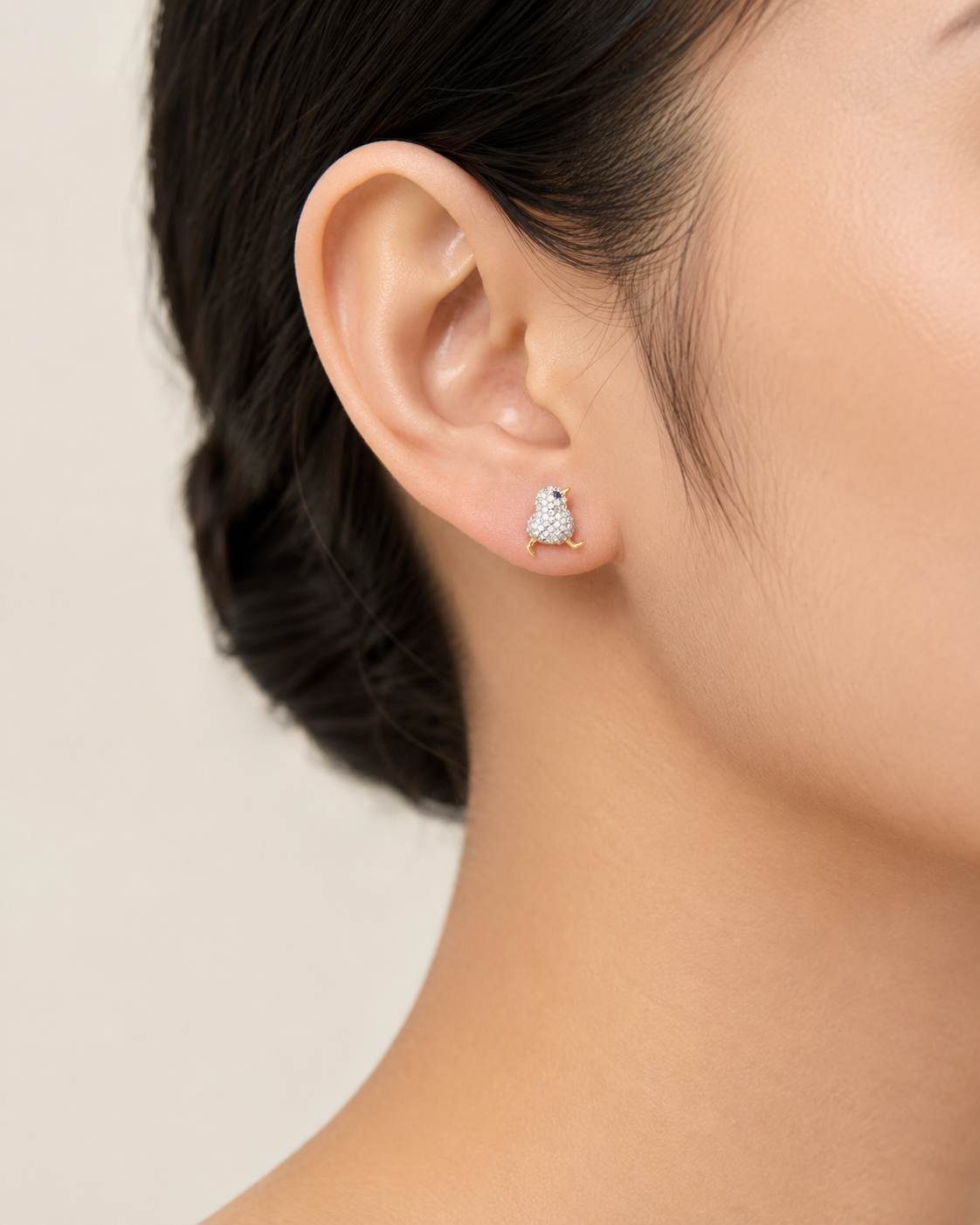 CARV. two-tone bird stud earrings with blue stone eye worn on ear