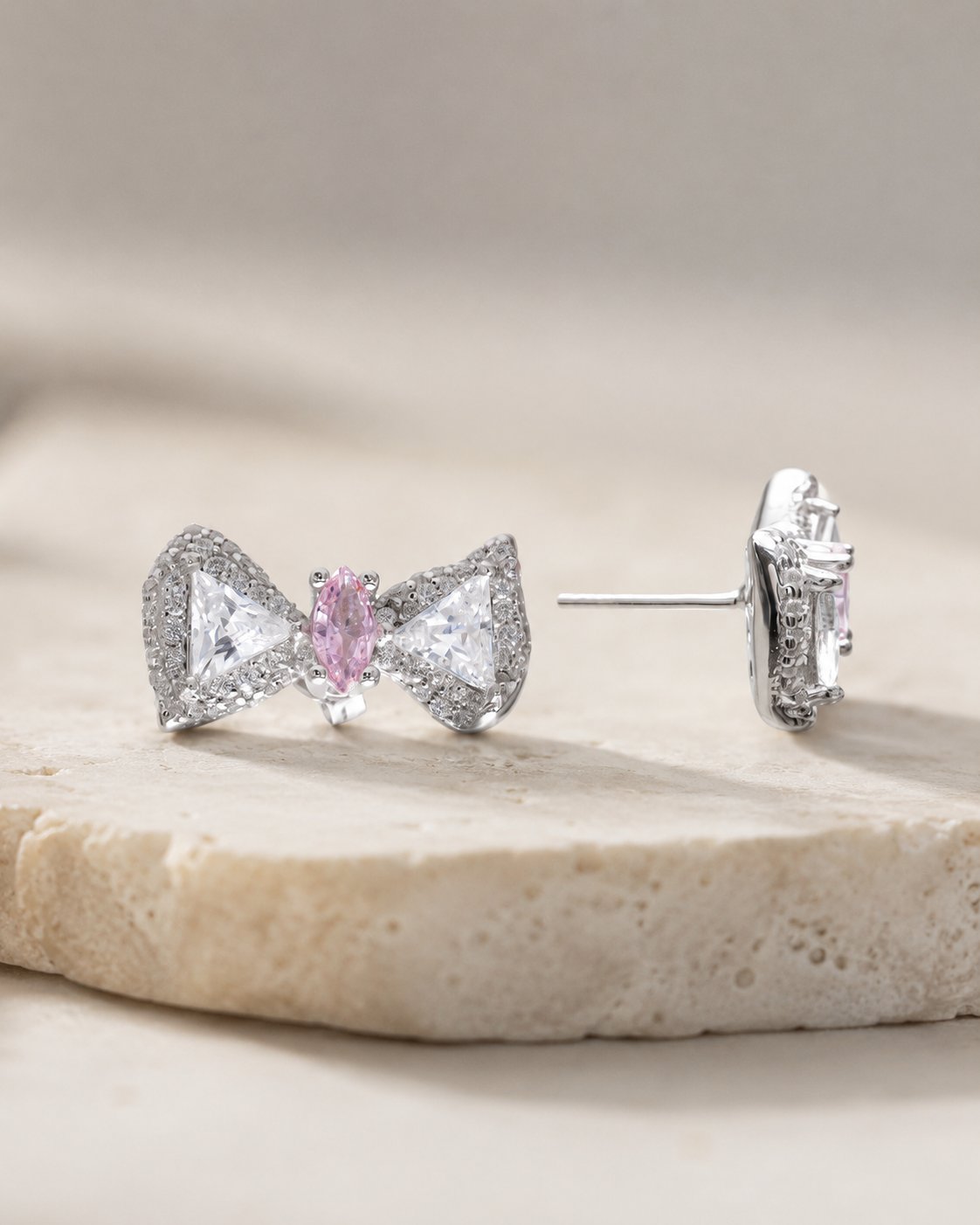 CARV. silver bow stud earrings with pink centre stone, pavé bow shape and side profile display