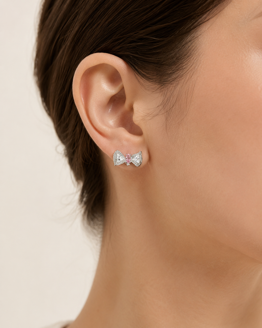 CARV. silver bow stud earrings worn on ear with pink centre stone and pavé bow detail