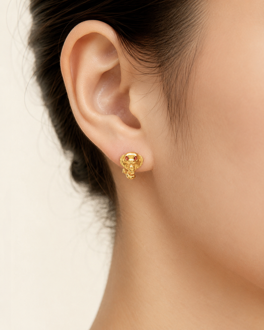 CARV. gold cobra stud earrings with red stone eyes worn on ear close-up