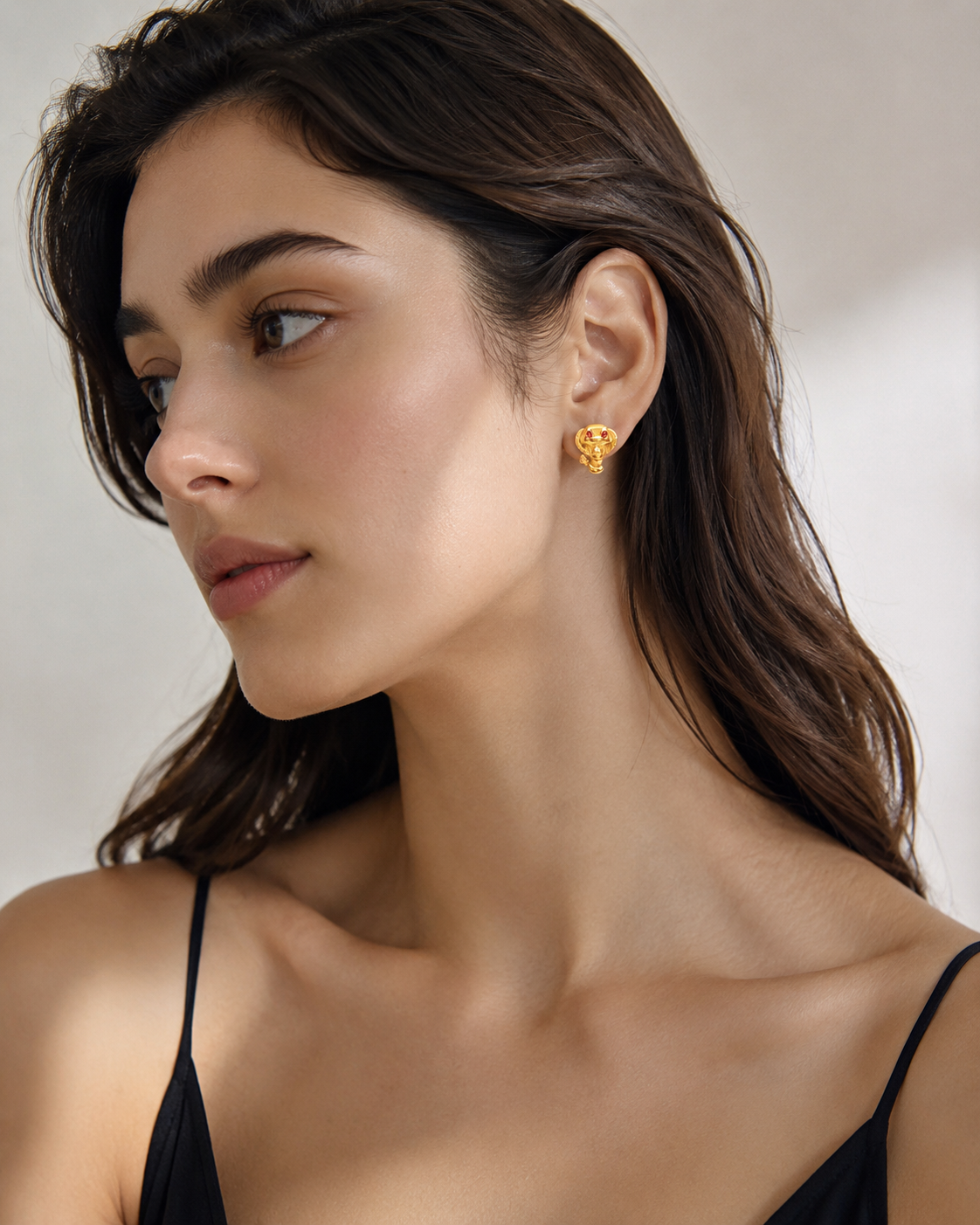 CARV. gold cobra stud earrings with sculpted snake head detail worn on ear