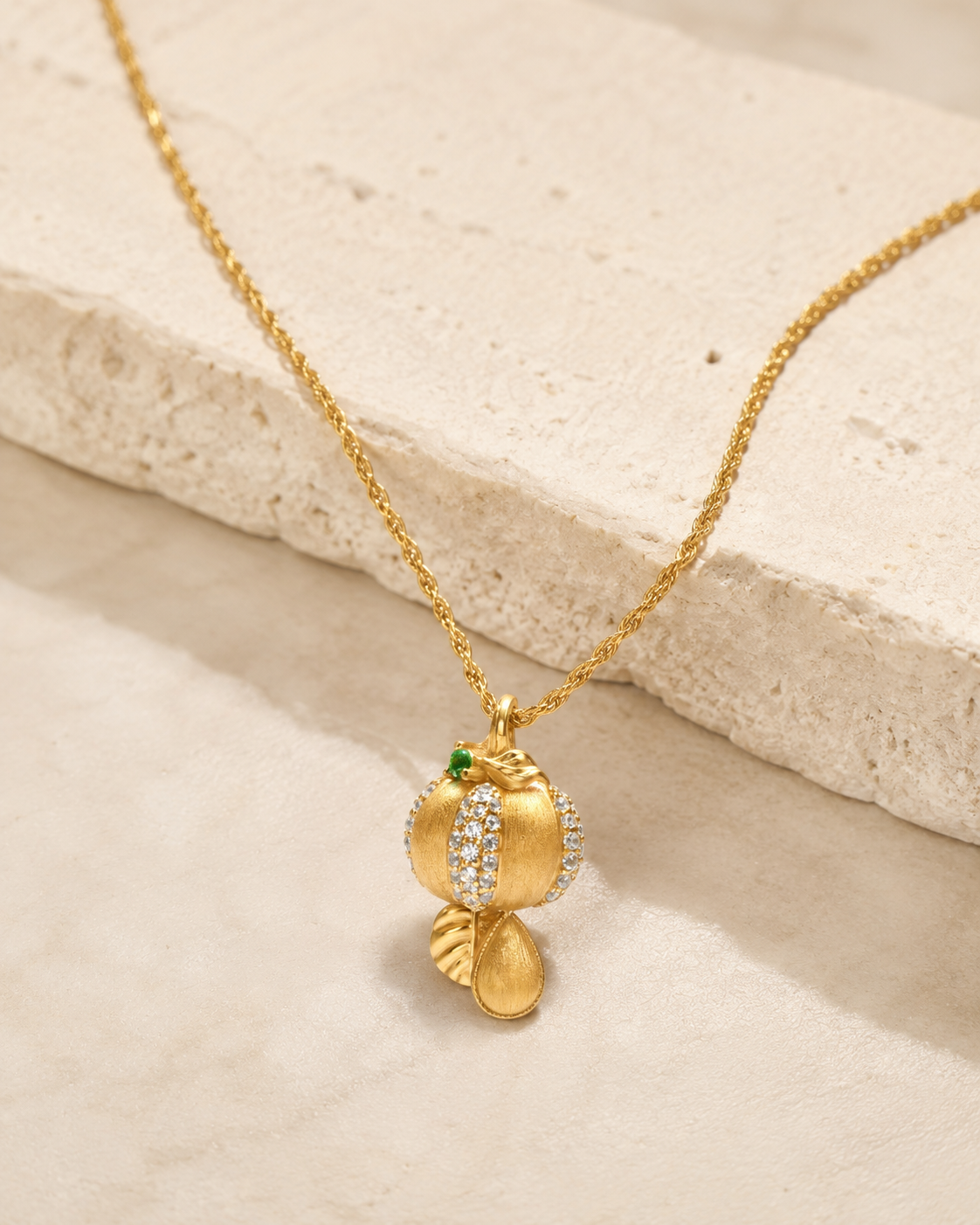 CARV. gold pumpkin pendant necklace with green stone accent and textured pendant product display