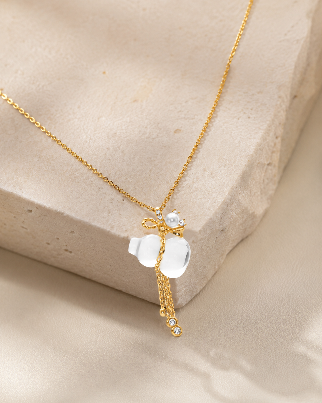 CARV. gold pendant necklace with white crystal charm, floral top detail and tassel drop product display