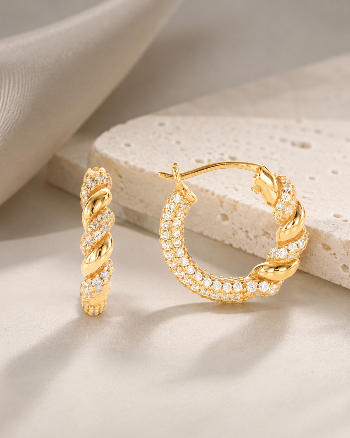 CARV. gold twisted pavé hoop earrings with rope twist detail on product display