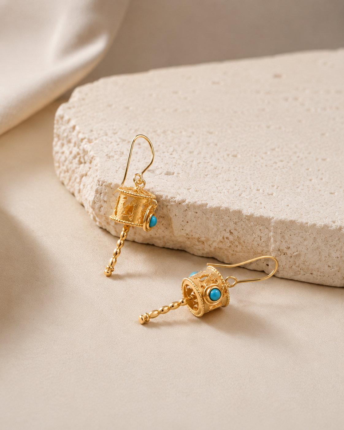 CARV. gold lantern drop earrings with turquoise stone detail and dangling beaded chain displayed on stone surface