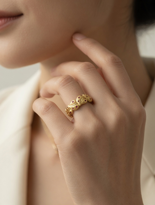 CARV. gold leaf band ring worn on hand with red stone accents and sculptural leaf design