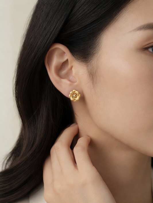 CARV. gold flower stud earrings worn on ear with layered petal design and sculptural floral center