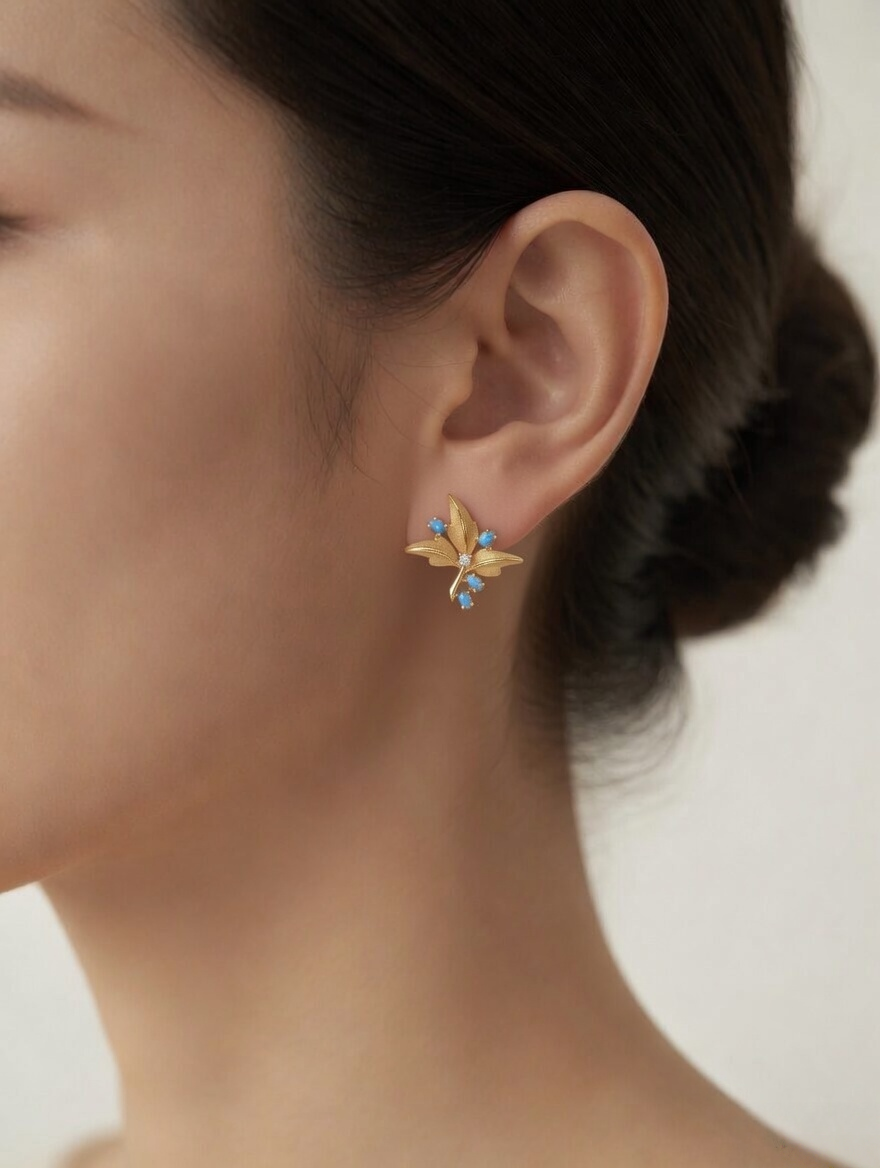 CARV. gold turquoise floral stud earrings with blue stone accents worn on ear