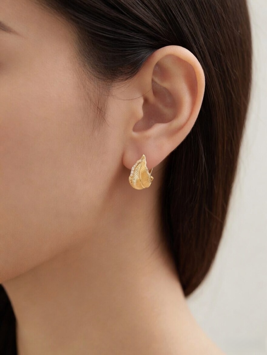 CARV. gold leaf stud earrings with pavé detail worn on ear close-up